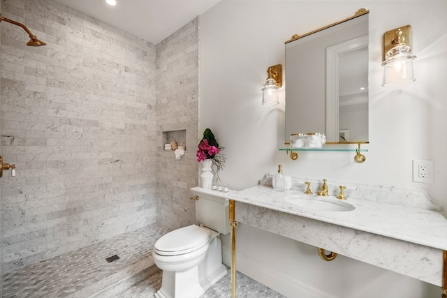 bathroom with vanity, tiled shower, and toilet