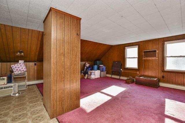 additional living space featuring wooden walls, vaulted ceiling, a wall unit AC, and a baseboard heating unit