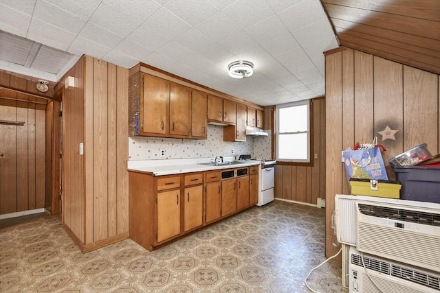 kitchen featuring wooden walls, a wall mounted air conditioner, white range, and sink