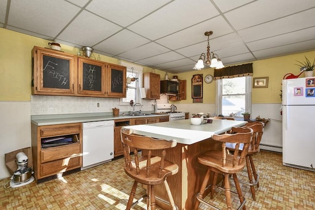 kitchen featuring a drop ceiling, pendant lighting, white appliances, and sink