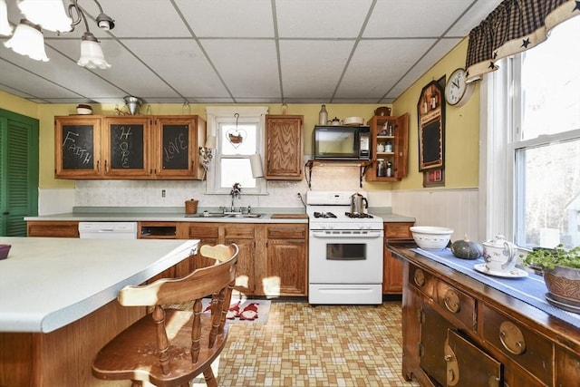 kitchen featuring a paneled ceiling, sink, white appliances, and hanging light fixtures