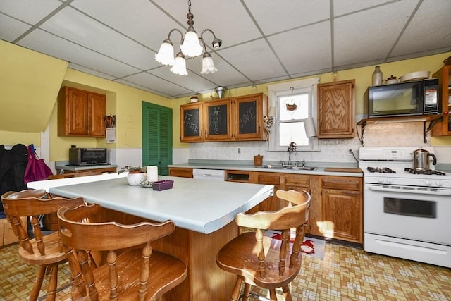 kitchen featuring a chandelier, a drop ceiling, decorative light fixtures, and white appliances