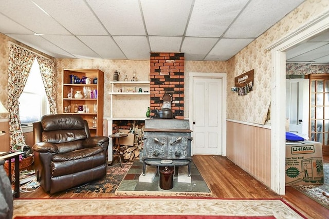 living area with hardwood / wood-style flooring, a drop ceiling, and wooden walls