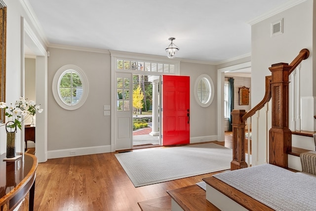 foyer entrance featuring a notable chandelier, crown molding, and light hardwood / wood-style floors