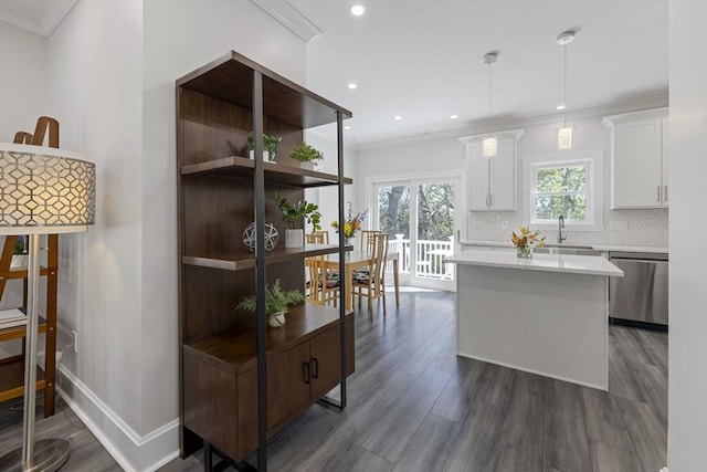 kitchen featuring stainless steel dishwasher, crown molding, a center island, light countertops, and a sink