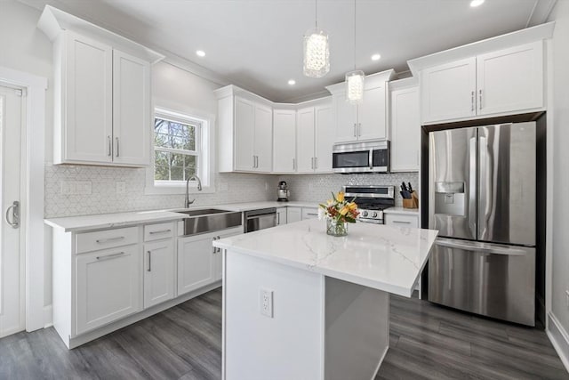 kitchen featuring a kitchen island, dark wood-type flooring, white cabinets, a sink, and stainless steel appliances