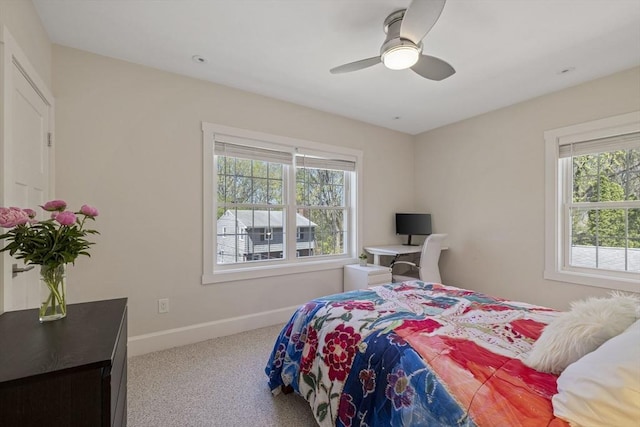 carpeted bedroom with a ceiling fan, baseboards, and multiple windows