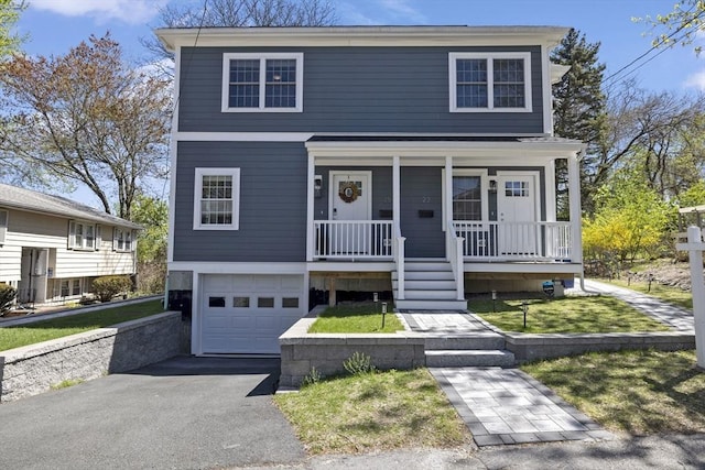 view of front of house featuring covered porch, an attached garage, a front yard, and aphalt driveway