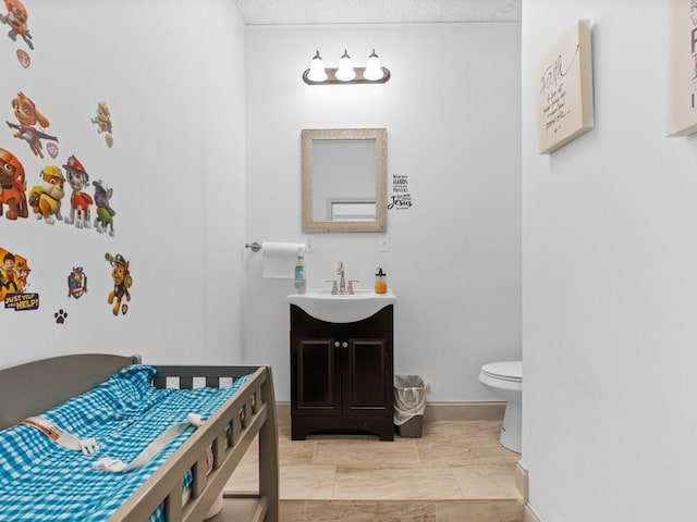 bathroom with vanity, baseboards, and toilet