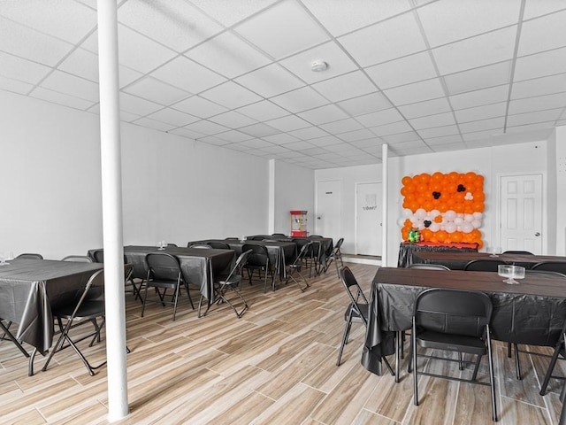 dining space with a paneled ceiling and light wood-style flooring