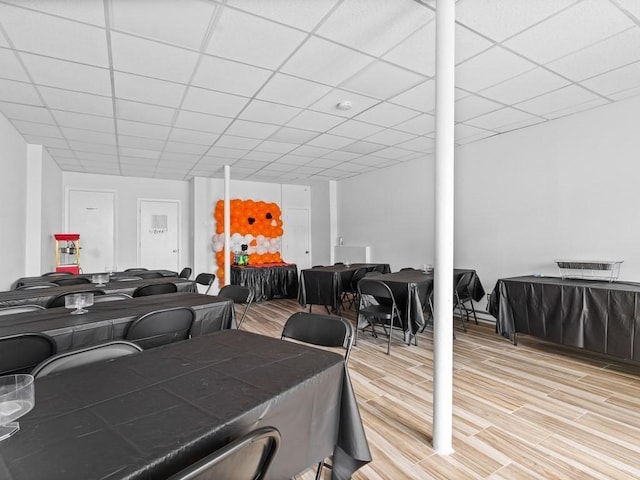 dining room featuring light wood-type flooring and a paneled ceiling