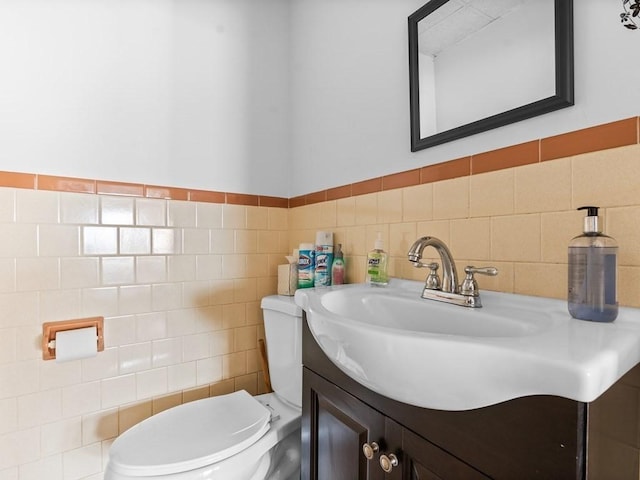 half bath featuring vanity, toilet, and tile walls