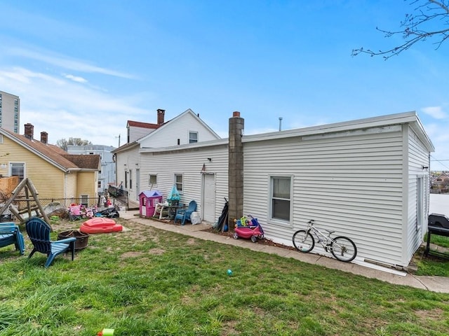 back of house with fence, a patio, a chimney, and a yard
