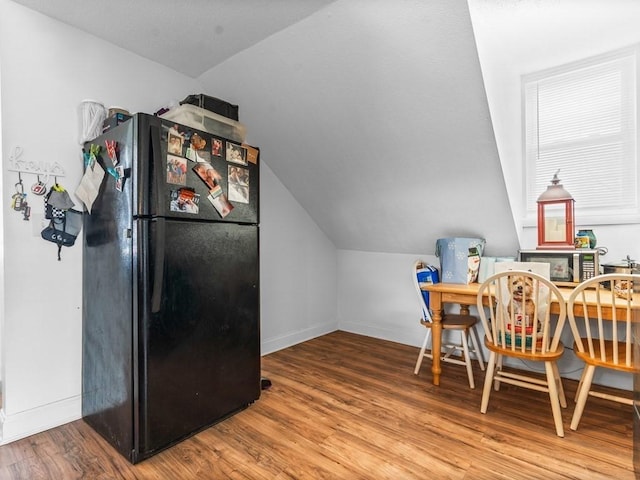 dining room featuring baseboards, wood finished floors, and lofted ceiling