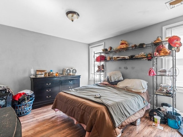 bedroom featuring visible vents, wood finished floors, and multiple windows