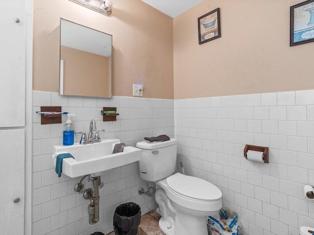 half bathroom with toilet, tile patterned floors, tile walls, and wainscoting