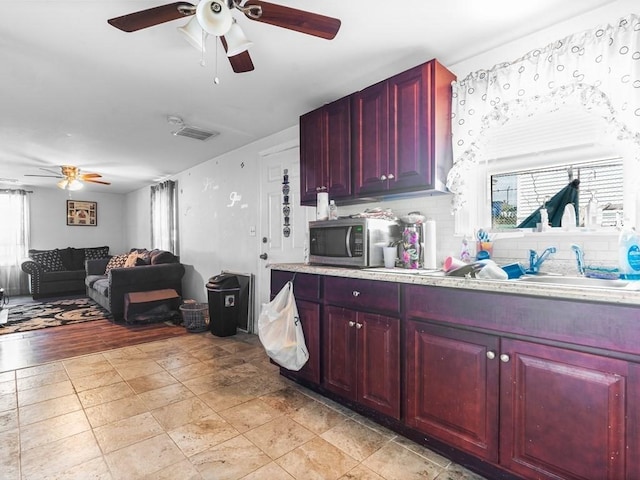 kitchen featuring visible vents, stainless steel microwave, a ceiling fan, and reddish brown cabinets