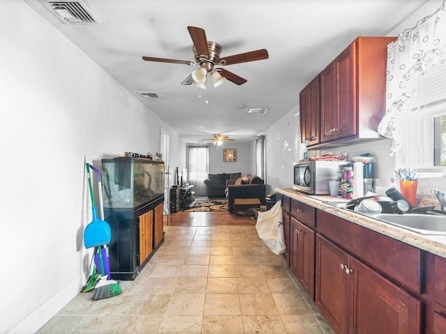 kitchen with a ceiling fan, visible vents, dark brown cabinets, light countertops, and stainless steel microwave
