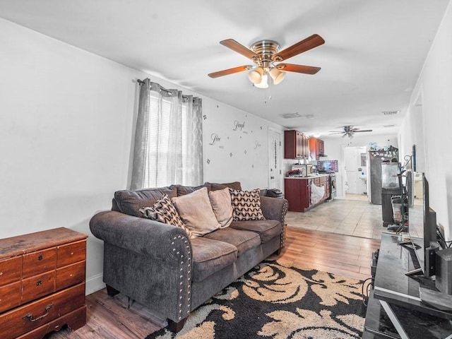 living area with visible vents, a ceiling fan, and light wood finished floors