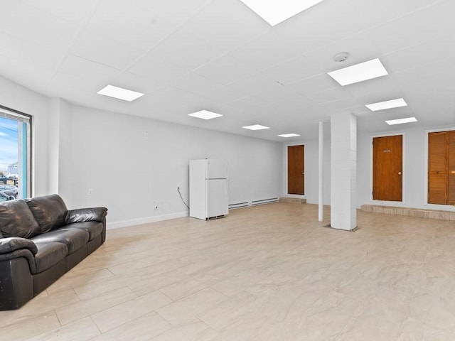 living area featuring baseboards, a drop ceiling, and baseboard heating