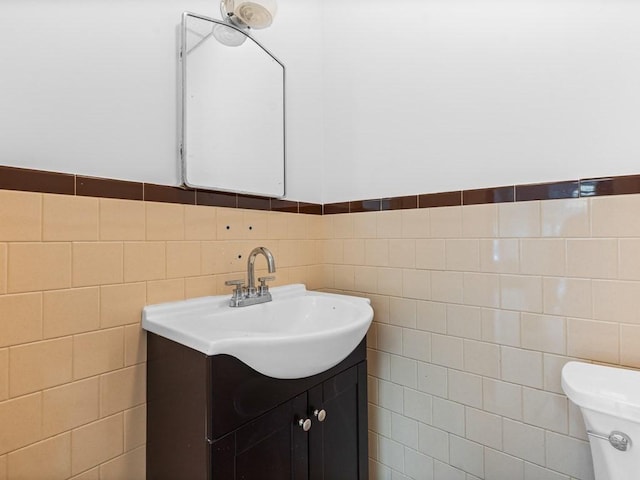 half bathroom with tile walls, vanity, and toilet