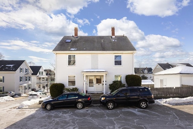 colonial home featuring a residential view, a chimney, and fence
