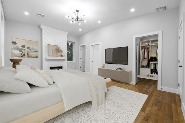 1442 Washington St, Canton, MA 02021 - bedroom with a chandelier, a spacious closet, wood finished floors, recessed lighting, and a large fireplace