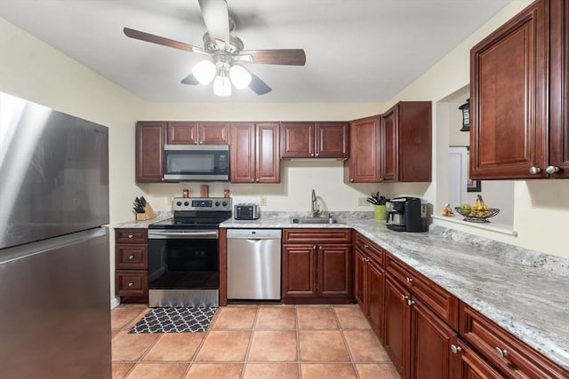 kitchen featuring light stone countertops, stainless steel appliances, sink, light tile patterned flooring, and ceiling fan