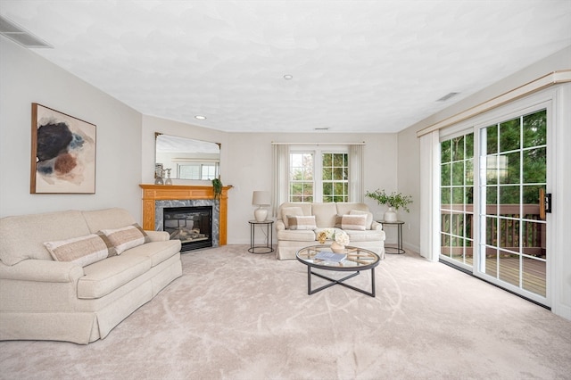 living room featuring a high end fireplace and light colored carpet