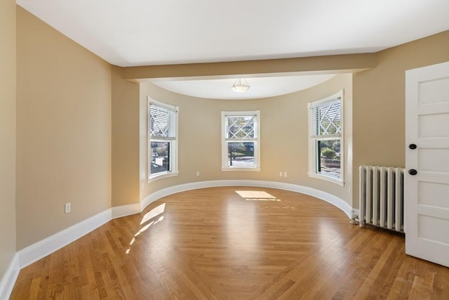 124 Boston Ave, Medford, MA 02155 - unfurnished room featuring radiator heating unit, plenty of natural light, and light wood-style floors