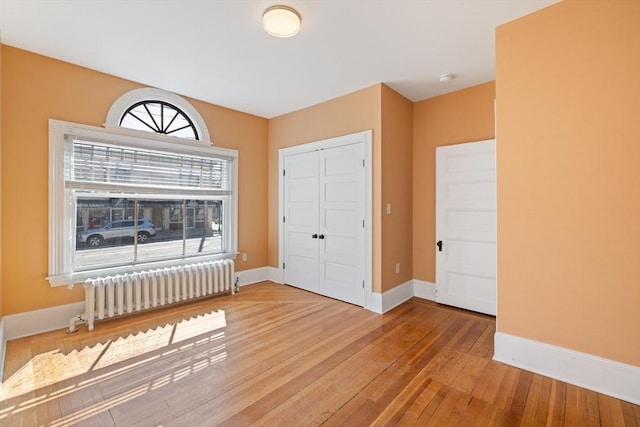 124 Boston Ave, Medford, MA 02155 - unfurnished bedroom featuring radiator, hardwood / wood-style floors, a closet, and baseboards