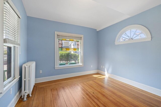 124 Boston Ave, Medford, MA 02155 - unfurnished room with radiator heating unit, healthy amount of natural light, and hardwood / wood-style flooring