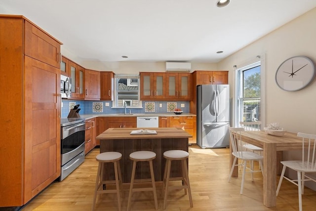 124 Boston Ave, Medford, MA 02155 - kitchen featuring stainless steel appliances, a wall mounted air conditioner, glass insert cabinets, light wood-style flooring, and recessed lighting