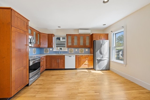 124 Boston Ave, Medford, MA 02155 - kitchen featuring appliances with stainless steel finishes, a wall mounted air conditioner, light wood-type flooring, glass insert cabinets, and recessed lighting