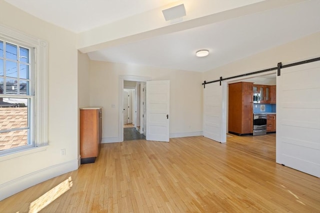 124 Boston Ave, Medford, MA 02155 - unfurnished room featuring light wood-style floors, a barn door, plenty of natural light, and baseboards