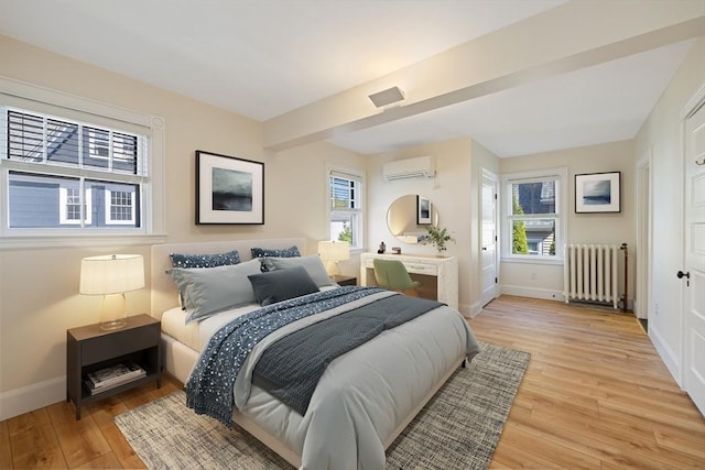 124 Boston Ave, Medford, MA 02155 - bedroom featuring radiator, baseboards, a wall mounted air conditioner, and light wood finished floors