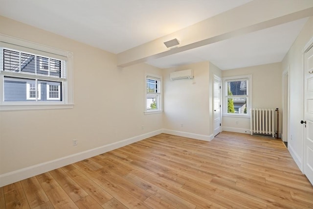 124 Boston Ave, Medford, MA 02155 - spare room with radiator, a wall unit AC, baseboards, and light wood-style flooring