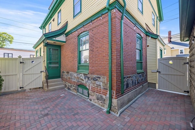 124 Boston Ave, Medford, MA 02155 - view of home's exterior with a gate, stone siding, entry steps, a patio area, and brick siding