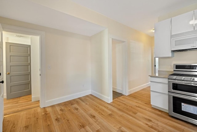 124 Boston Ave, Medford, MA 02155 - kitchen with white microwave, range with two ovens, baseboards, and light wood-type flooring