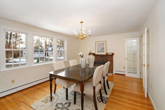 dining space featuring a chandelier, light wood-type flooring, and a baseboard radiator