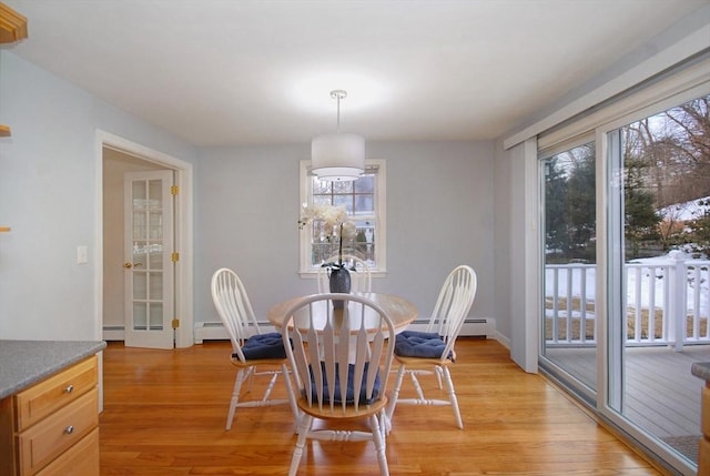 dining space with a baseboard heating unit, light wood-style floors, and a healthy amount of sunlight