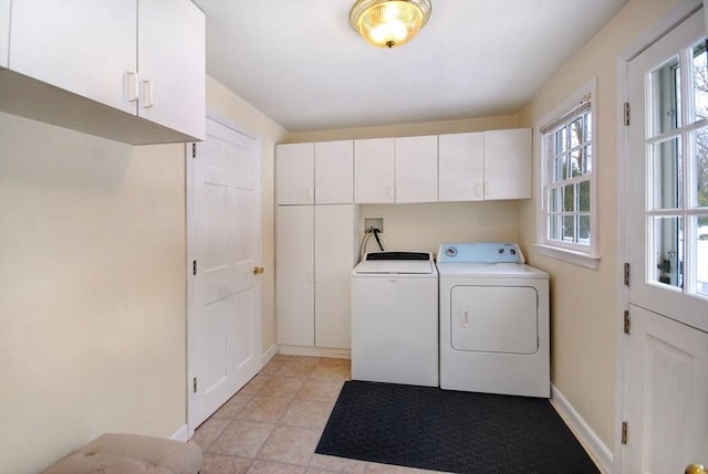 laundry area with light tile patterned floors, baseboards, cabinet space, and washer and clothes dryer