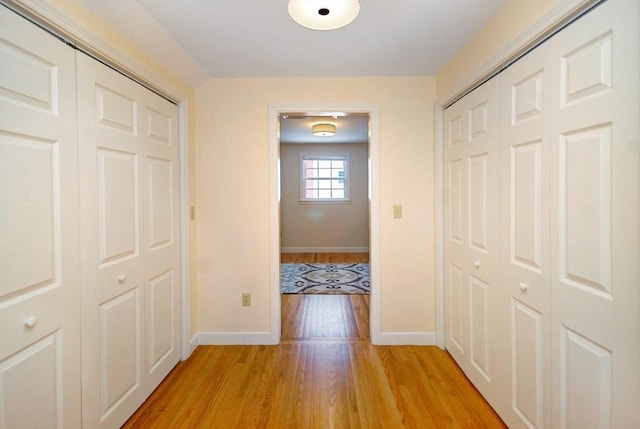 hallway with baseboards and light wood-style floors