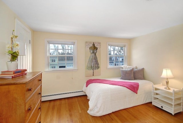 bedroom with a baseboard radiator, multiple windows, and wood finished floors