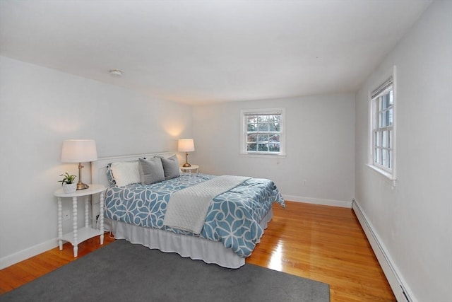 bedroom with a baseboard radiator, baseboards, and wood finished floors