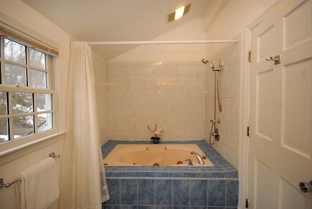 bathroom with a wealth of natural light, lofted ceiling, and a combined bath / shower with jetted tub