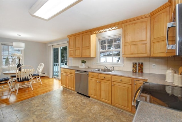 kitchen with decorative light fixtures, light countertops, decorative backsplash, appliances with stainless steel finishes, and a sink