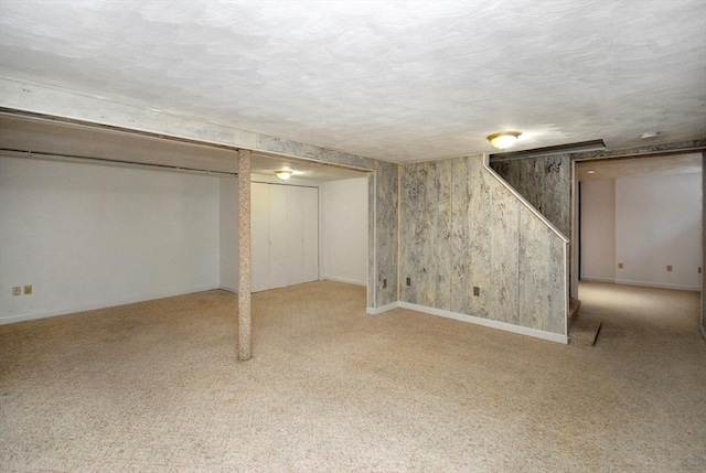 finished below grade area featuring baseboards, carpet floors, and a textured ceiling