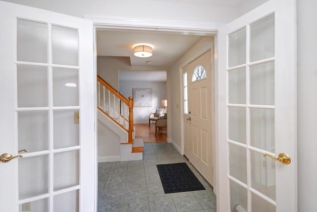 tiled entrance foyer featuring baseboards and stairs