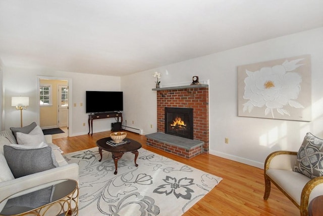 living area featuring a baseboard heating unit, wood finished floors, baseboards, and a fireplace